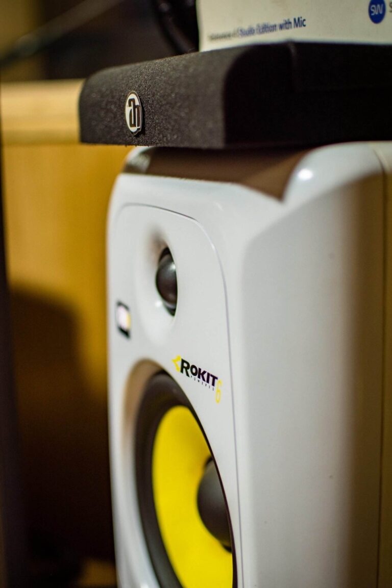 Vue rapprochée d'un haut-parleur de studio Rokit 6 avec un cône jaune, positionné à proximité d'un autre appareil audio.