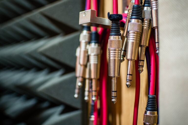 Gros plan de plusieurs câbles de prise audio suspendus, avec des panneaux de mousse acoustique visibles en arrière-plan.