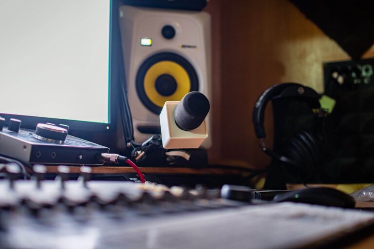 Gros plan d'une configuration de studio d'enregistrement avec un microphone, des haut-parleurs de contrôle, une interface audio avec des câbles et des écouteurs sur le bureau.