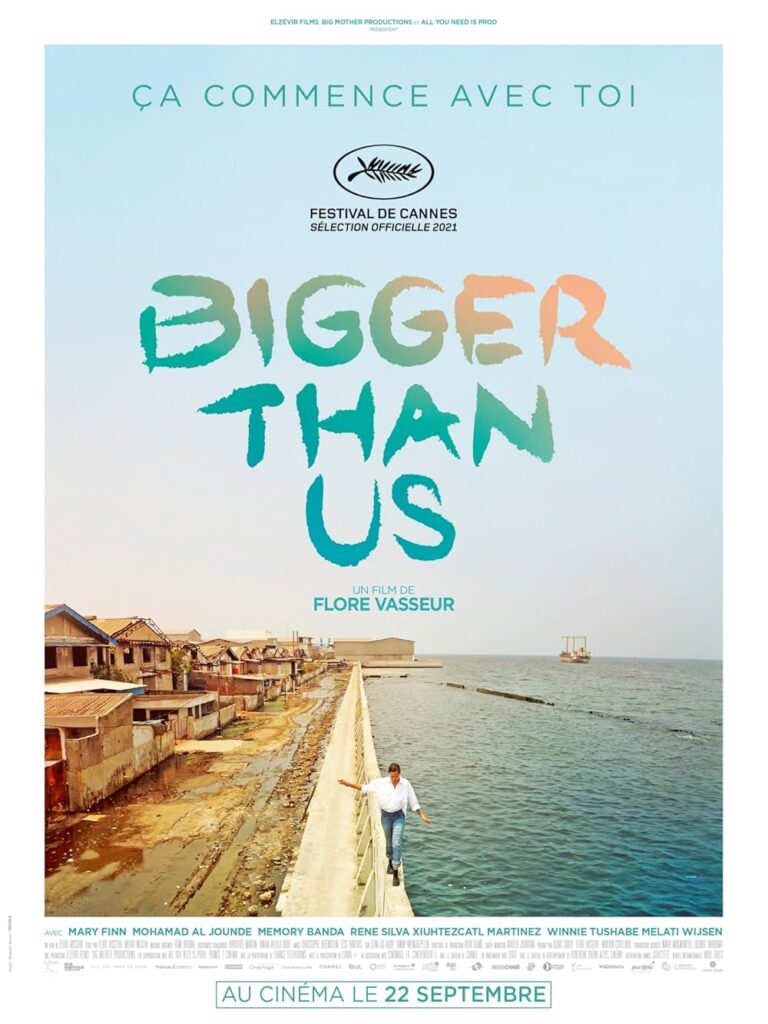 Poster for the film "Bigger Than Us," with a person walking on a pier towards a coastal town. Text highlights festival selections and release date. The movie features exceptional work by a top dubbing studio to ensure an authentic viewing experience in multiple languages.