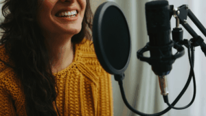 A person in a yellow knit sweater speaks or sings into a microphone with a pop filter, possibly working on Dubbing Services for a project set in Morocco.